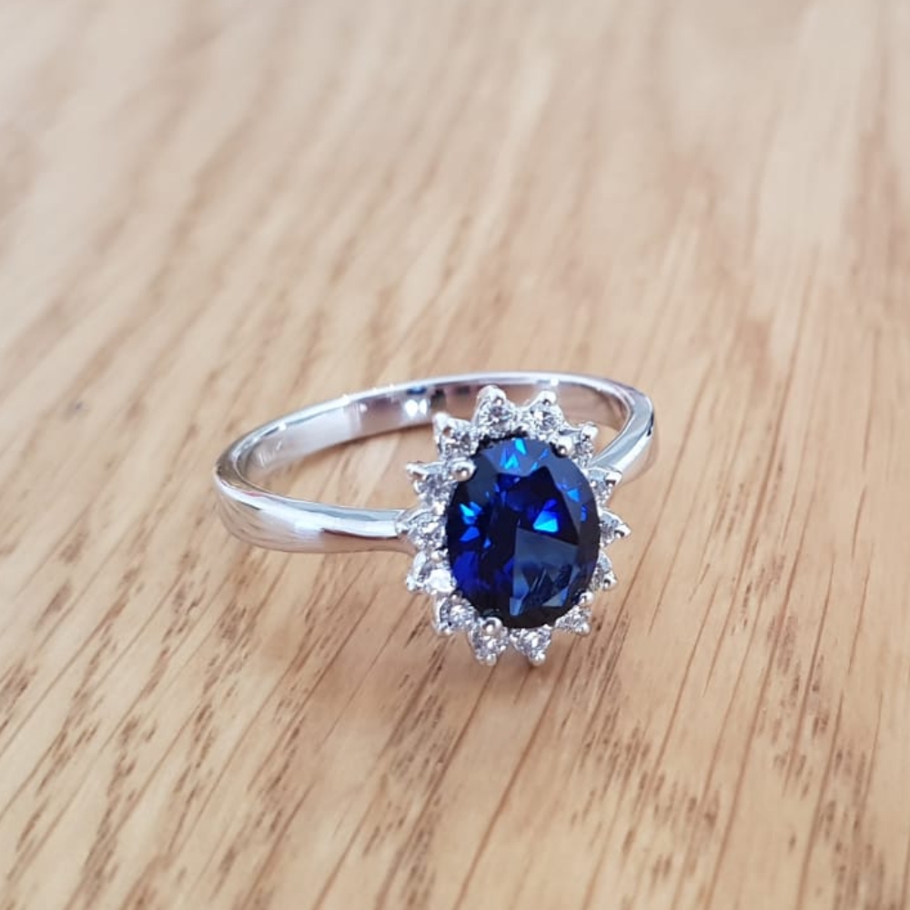 תמונה אמיתית של טבעת דיאנה משובצת אבן ספיר כחולה ו14 יהלומים מסביב